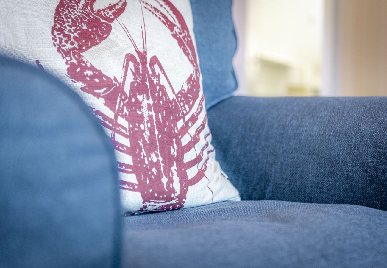 Close-up of a charming lobster-print cushion resting on a chair—adding a fun, coastal-inspired accent to the room’s decor.