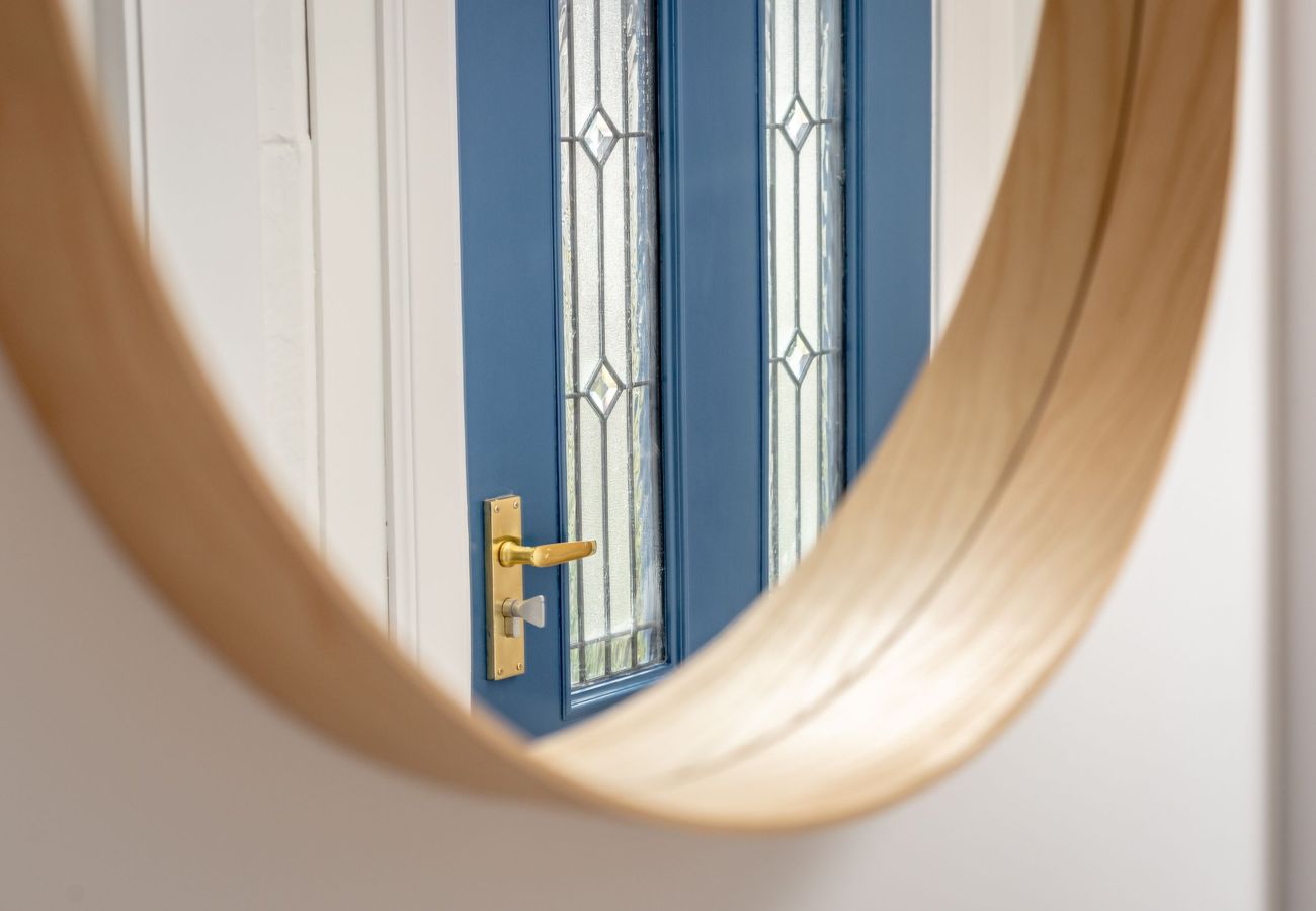 Blue front door with glass panels and gold handle, seen in round mirror.