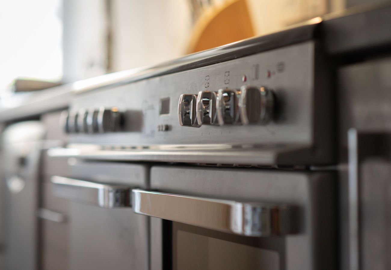Close-up of a stainless steel oven and hob with chrome dials and contemporary finish