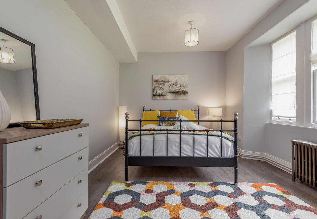 Cheerful bedroom with bold accents, patterned rug, double bed, and a mix of classic and modern furnishings.
