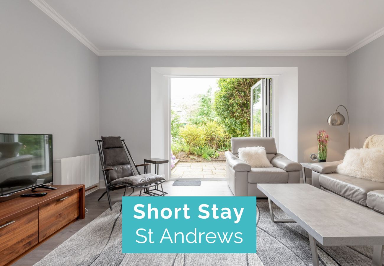 Tastefully decorated open-plan lounge/diner with plush seating, large rug, wood accents, and access to garden area.