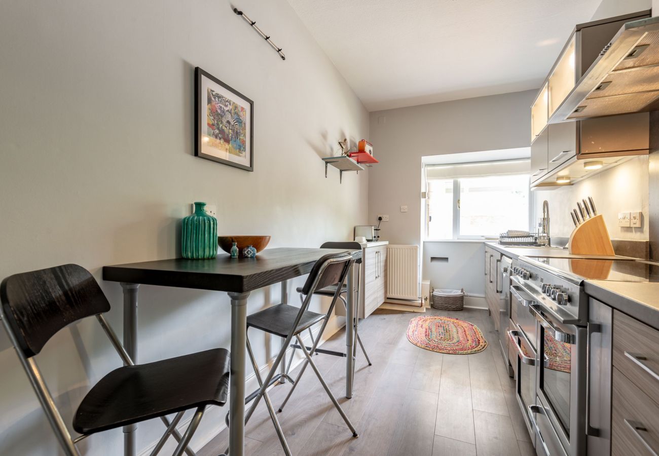 Sleek kitchen with integrated microwave, modern cabinetry, and compact dining space with black folding chairs.