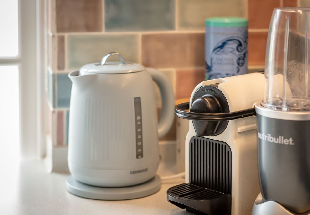 Close-up of countertop with Kenwood kettle, Nespresso machine, and Nutribullet against colourful tiled backsplash in St Andrews kitchen