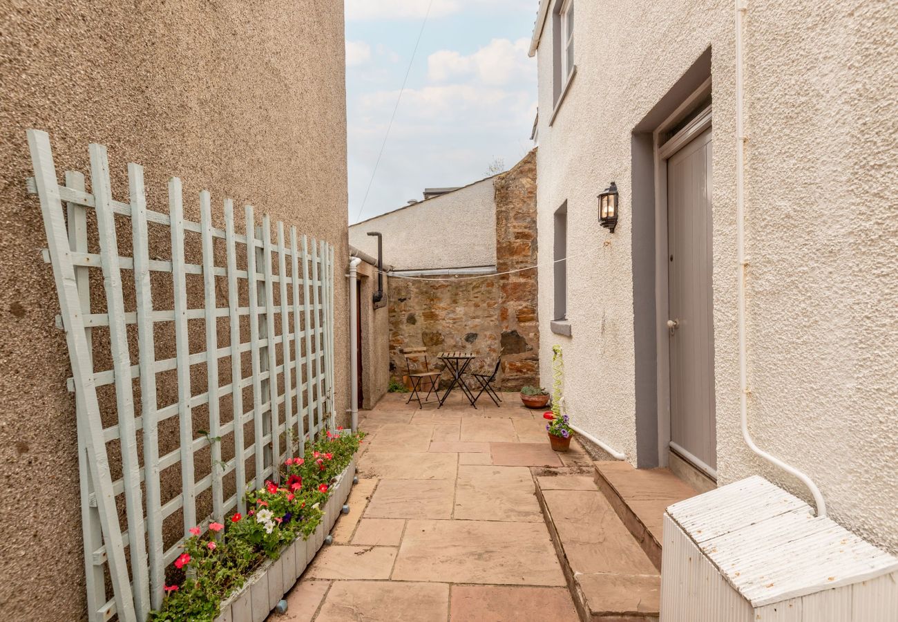 Gate and paved patio with planters beside the side door at Earls Lodge holiday cottage, Earlsferry.