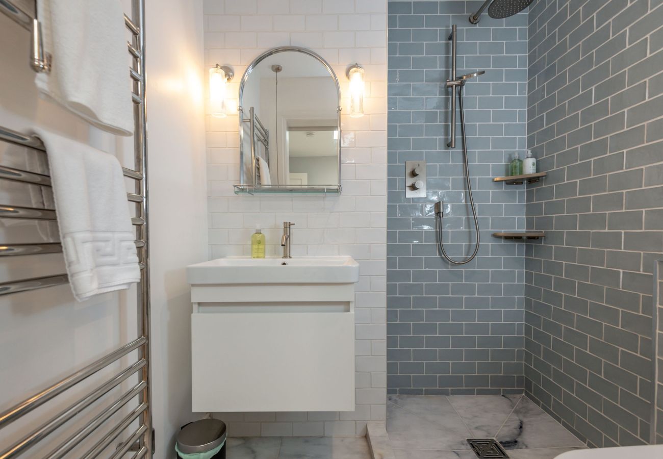 Contemporary shower room with grey subway tiles, rainfall head and vanity unit in St Andrews apartment.