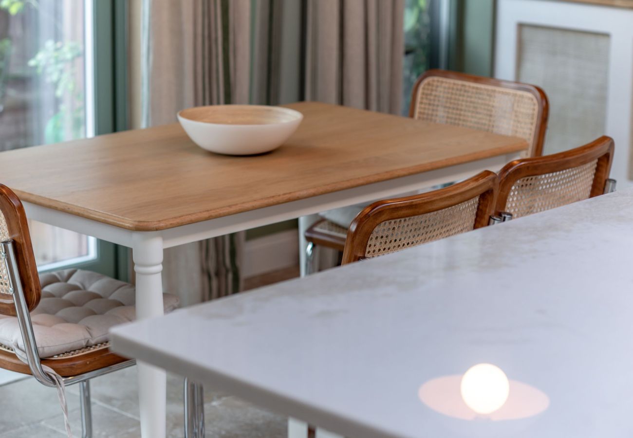 Bright dining table with cane-back chairs beside garden-view windows in open-plan space, 42 Lade Braes, St Andrews.