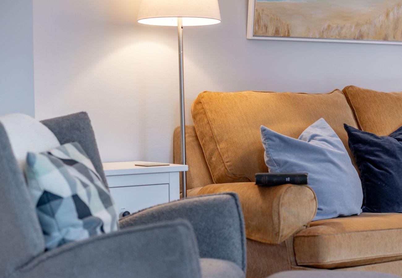 Comfy sofa with blue cushions, armchair and floor lamp in relaxing lounge at 42 Lade Braes, St Andrews.