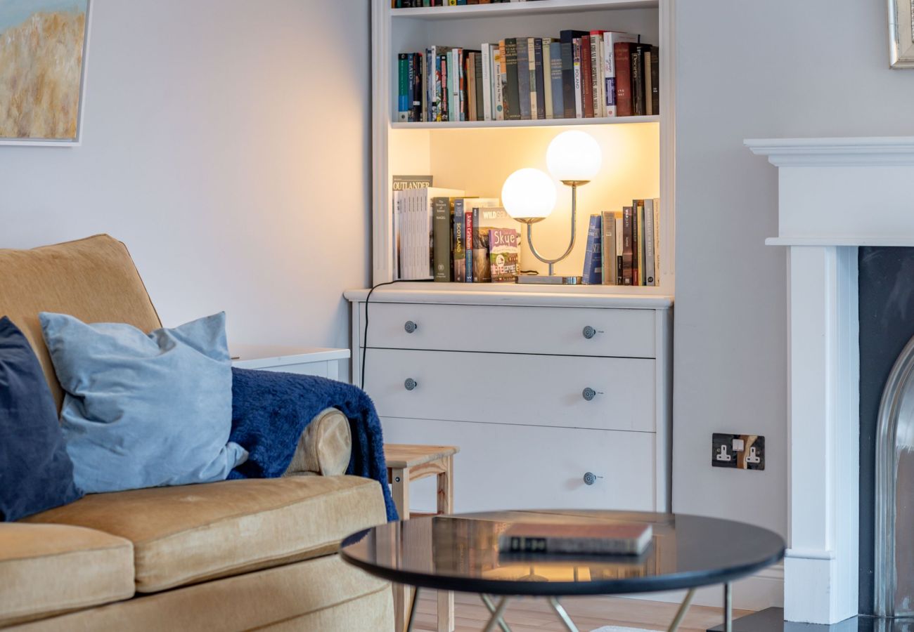 Inviting lounge with built-in shelves, soft lighting and coffee table near fireplace at 42 Lade Braes, St Andrews.